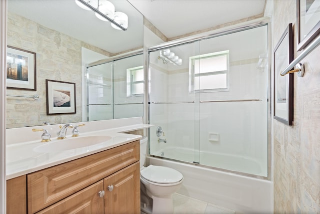 full bath featuring tile patterned flooring, combined bath / shower with glass door, vanity, and toilet