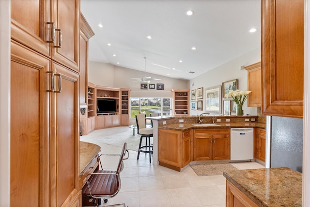 kitchen featuring a breakfast bar area, white dishwasher, stone countertops, a peninsula, and a sink