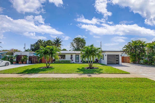 view of front of home with a front yard, decorative driveway, fence, and an attached garage