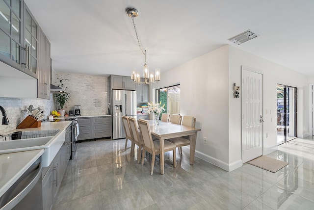 dining room with a chandelier, light tile patterned flooring, visible vents, and baseboards