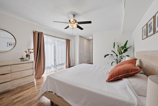 bedroom featuring a textured ceiling, a ceiling fan, light wood-style flooring, and access to exterior