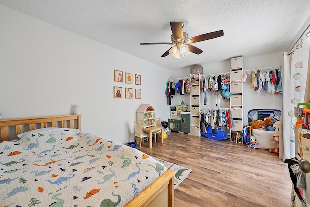 bedroom with a textured ceiling, ceiling fan, and wood finished floors