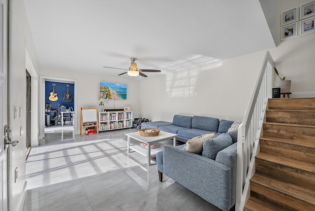 living area with ceiling fan and stairway