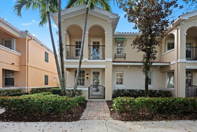 view of front of house featuring a tiled roof, a gate, and stucco siding