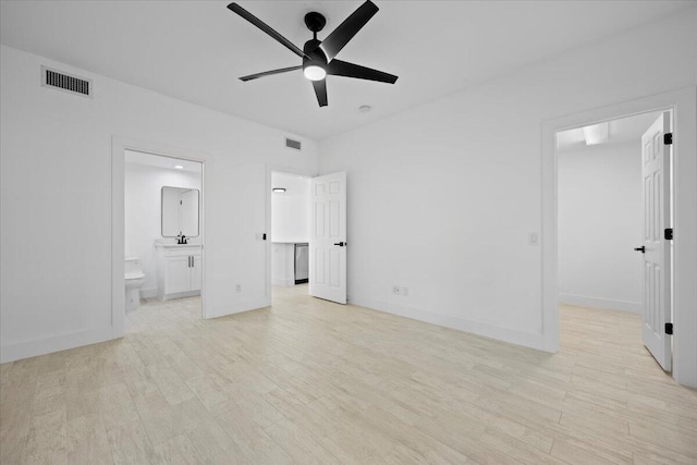 unfurnished bedroom featuring ensuite bathroom, light wood-type flooring, a walk in closet, and visible vents