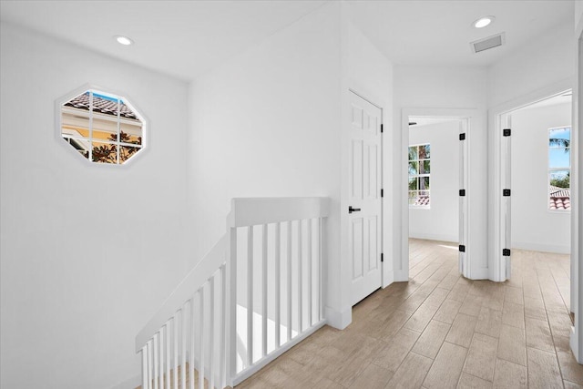 corridor with light wood-style flooring, plenty of natural light, visible vents, and recessed lighting