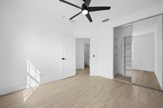 unfurnished bedroom featuring wood finished floors, visible vents, baseboards, a ceiling fan, and a closet