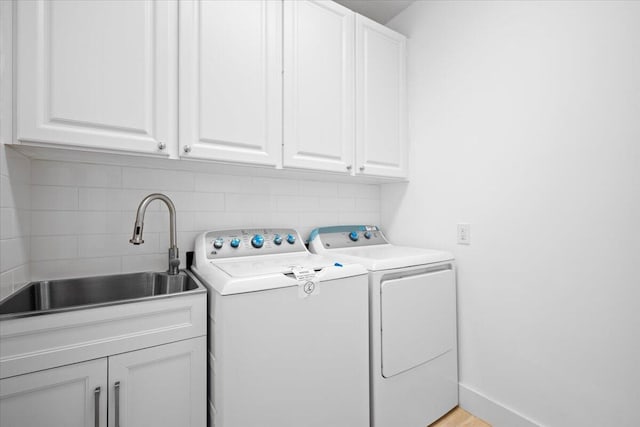 laundry room with separate washer and dryer, a sink, cabinet space, and baseboards