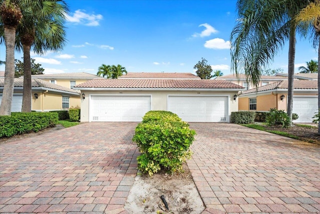 view of front of house with a garage, decorative driveway, a tiled roof, and stucco siding