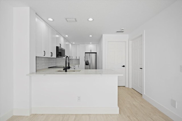 kitchen featuring visible vents, backsplash, appliances with stainless steel finishes, light wood-type flooring, and a peninsula