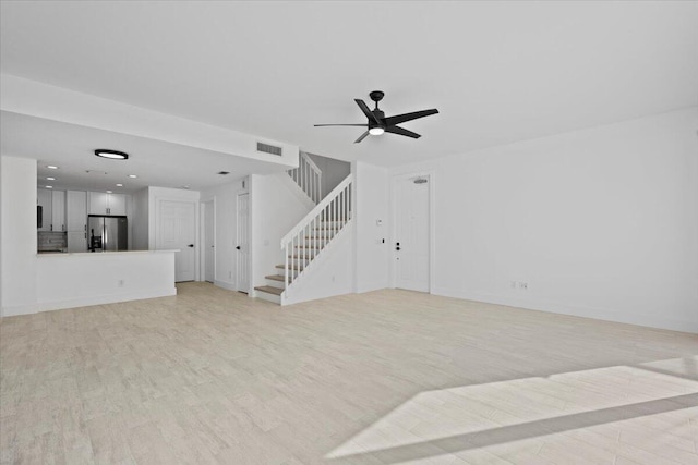 unfurnished living room featuring light wood-style flooring, visible vents, baseboards, stairs, and a ceiling fan