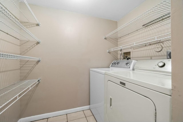 laundry area featuring laundry area, washer and clothes dryer, light tile patterned flooring, and baseboards