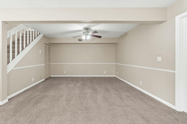 carpeted empty room featuring visible vents, ceiling fan, baseboards, and stairs