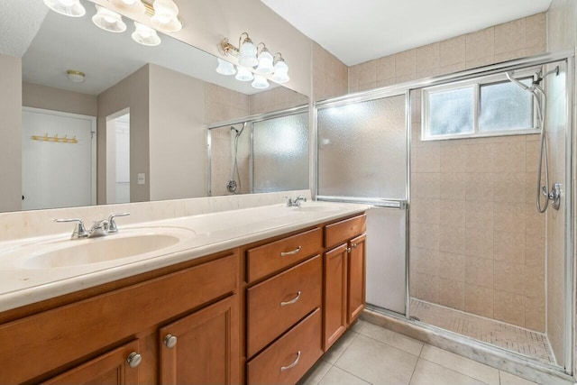 bathroom with double vanity, a stall shower, tile patterned flooring, and a sink