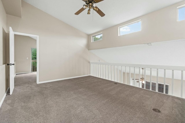 carpeted empty room featuring high vaulted ceiling, baseboards, and a ceiling fan