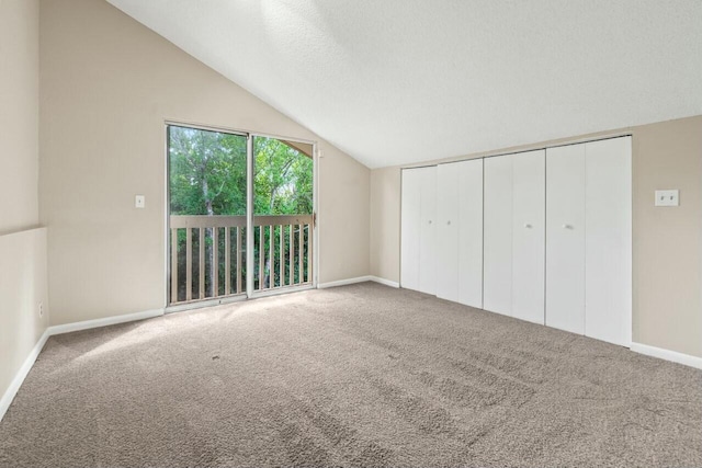 unfurnished bedroom featuring baseboards, access to exterior, vaulted ceiling, a textured ceiling, and carpet flooring