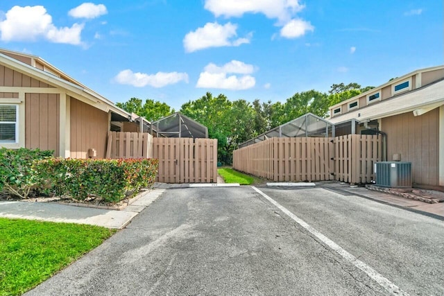 view of gate with central AC and fence