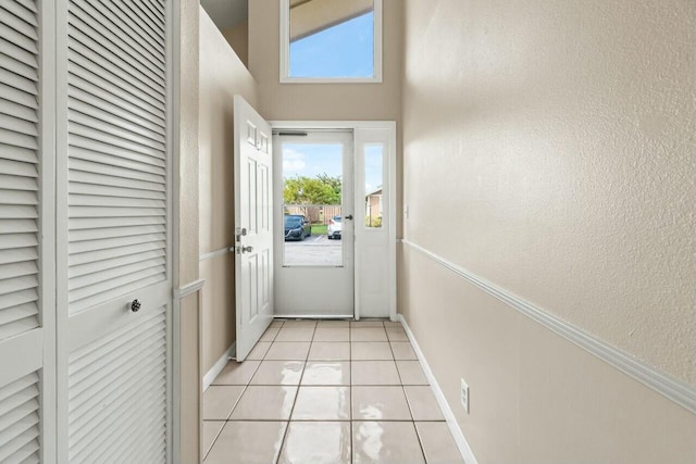 doorway to outside featuring light tile patterned floors, baseboards, and a textured wall