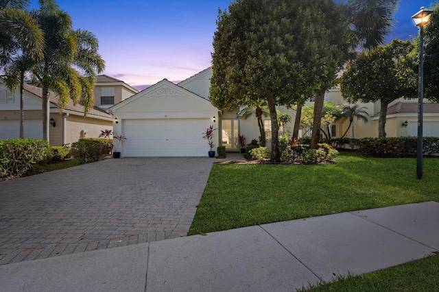 view of front of home featuring a garage, decorative driveway, a front yard, and stucco siding