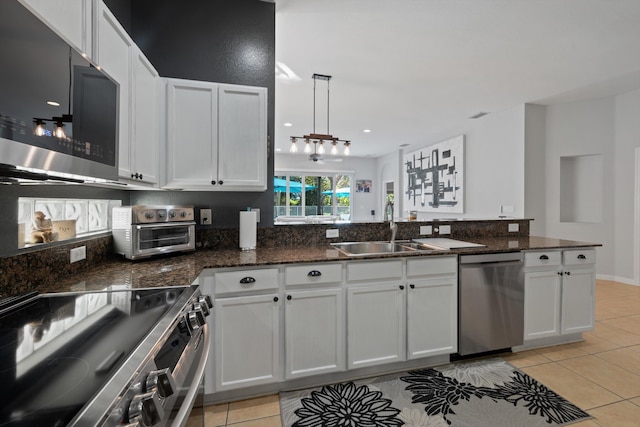 kitchen featuring stainless steel appliances, light tile patterned flooring, a sink, and white cabinets