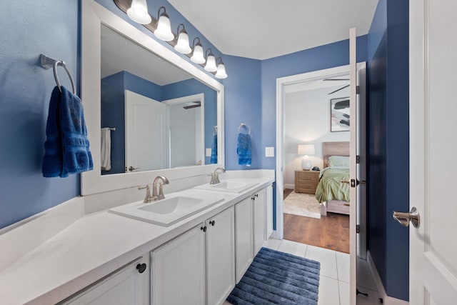 bathroom featuring tile patterned flooring, double vanity, a sink, and ensuite bathroom