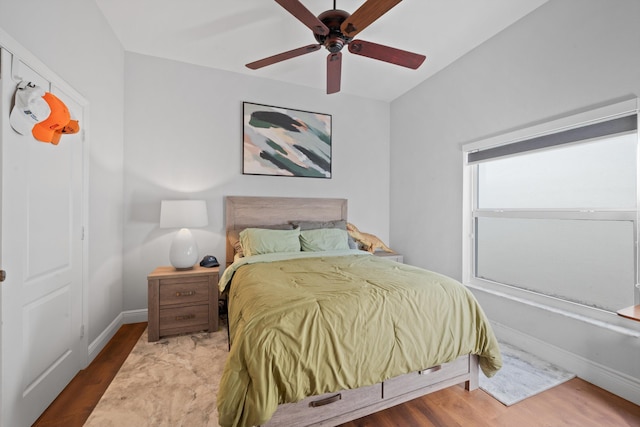 bedroom with a ceiling fan, baseboards, and wood finished floors