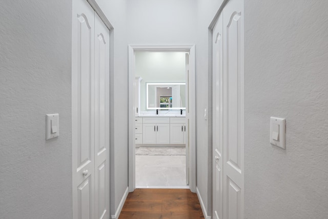 hallway with a textured wall, dark wood finished floors, and baseboards