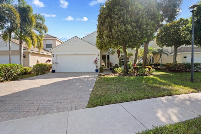 view of front of home with a garage, a front lawn, decorative driveway, and stucco siding