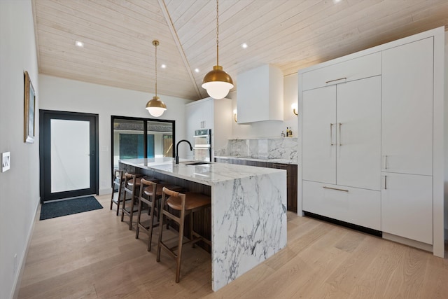 kitchen featuring light stone counters, decorative light fixtures, a spacious island, white cabinets, and modern cabinets