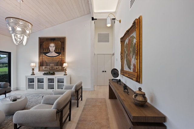 living area featuring visible vents, wooden ceiling, light wood-style flooring, an inviting chandelier, and vaulted ceiling