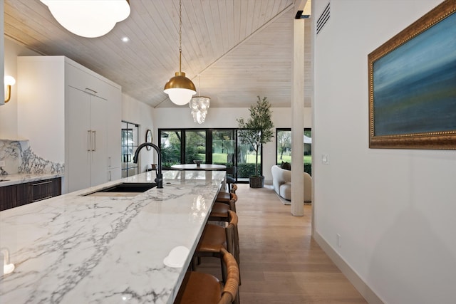 kitchen featuring pendant lighting, wooden ceiling, a sink, and light stone countertops