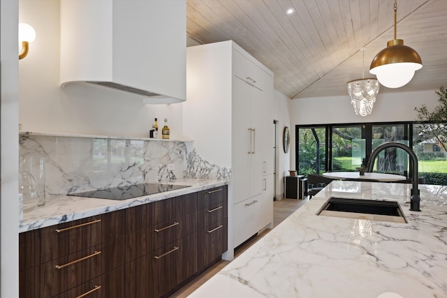 kitchen with tasteful backsplash, modern cabinets, hanging light fixtures, black electric cooktop, and a sink