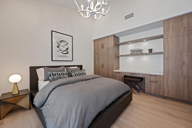 bedroom with a chandelier, light wood finished floors, and visible vents