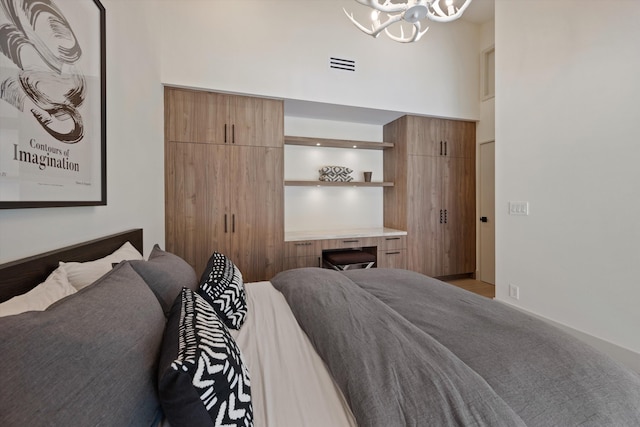 bedroom with visible vents, a high ceiling, and an inviting chandelier