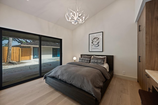 bedroom with access to outside, a notable chandelier, lofted ceiling, light wood-type flooring, and baseboards