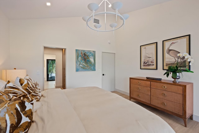 bedroom with high vaulted ceiling, a chandelier, and light wood finished floors