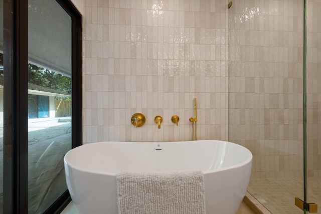 full bathroom featuring a freestanding tub, tile walls, and a shower stall