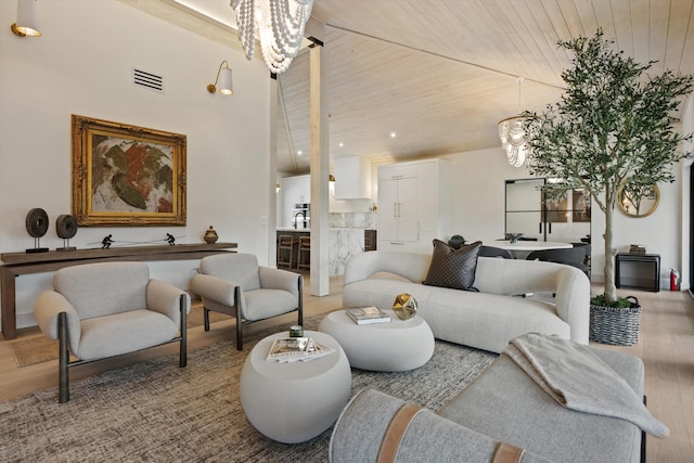 living area with a chandelier, wood ceiling, visible vents, and wood finished floors