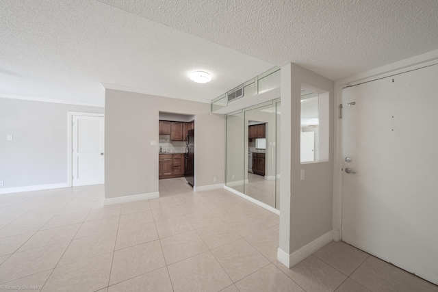 empty room with visible vents, a textured ceiling, baseboards, and light tile patterned floors