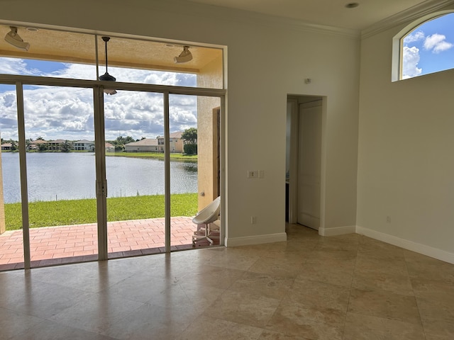 entryway with ornamental molding, a healthy amount of sunlight, a water view, and baseboards