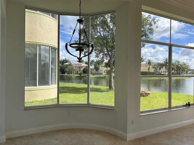 unfurnished dining area with a wealth of natural light, a water view, and baseboards