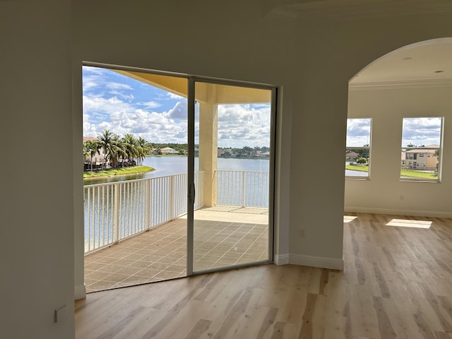 entryway with ornamental molding, a water view, baseboards, and wood finished floors