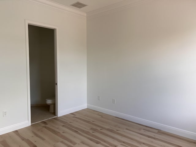 unfurnished bedroom featuring ornamental molding, light wood-style flooring, visible vents, and baseboards