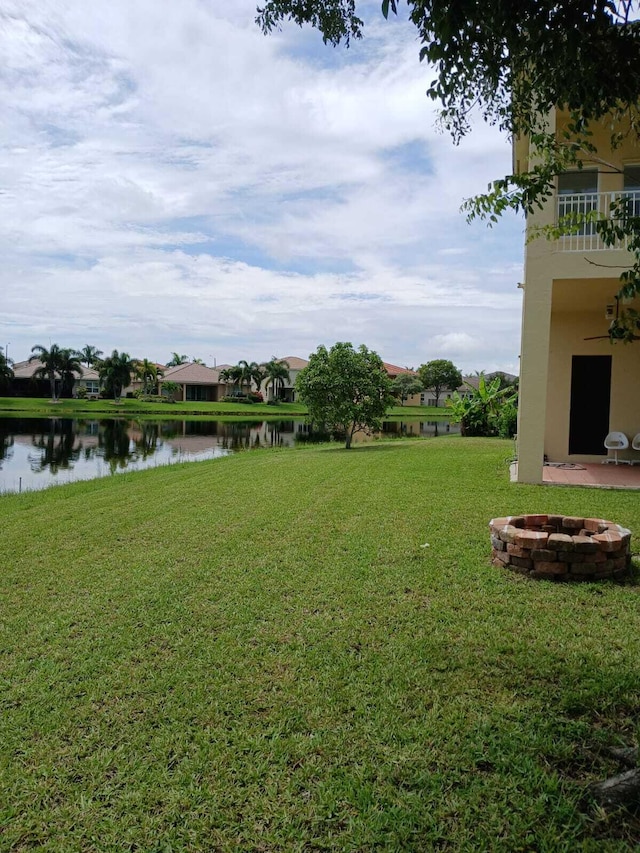 view of yard featuring a fire pit, a water view, a balcony, and a ceiling fan