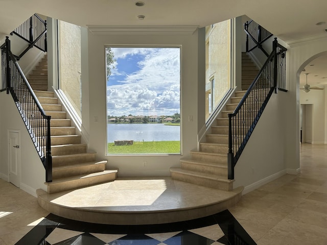 staircase with arched walkways, ornamental molding, a water view, and baseboards