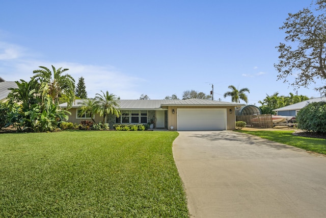 ranch-style house featuring driveway, an attached garage, metal roof, and a front yard