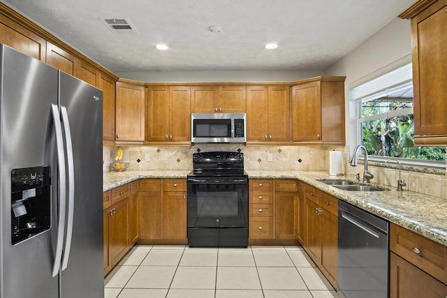 kitchen with stainless steel appliances, brown cabinets, a sink, and light tile patterned floors