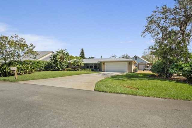 ranch-style home featuring driveway, an attached garage, and a front yard