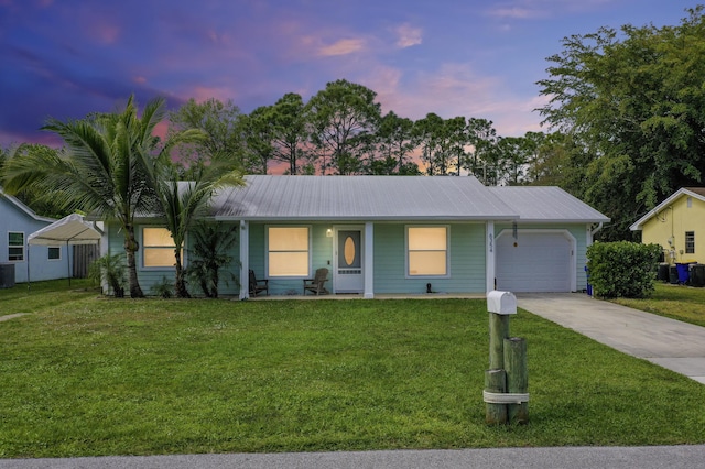 ranch-style home featuring an attached garage, metal roof, a front lawn, and concrete driveway