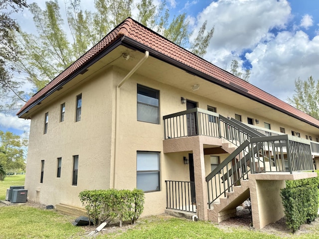 view of home's exterior with central AC, stairway, a tile roof, and stucco siding